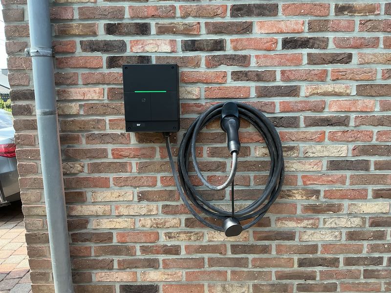 Borne de recharge murale avec câble enroulé sur un mur en briques