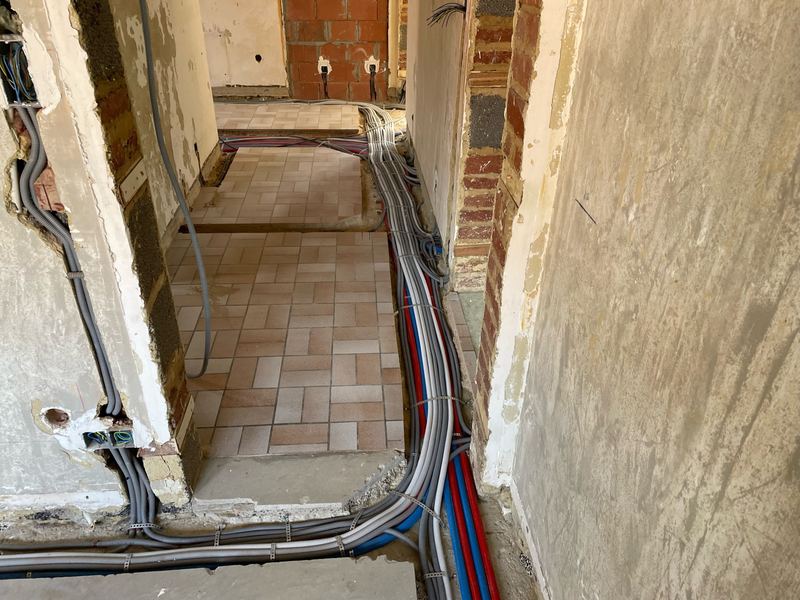 Gaines électriques et tuyauteries passant d’une pièce à l’autre au sol